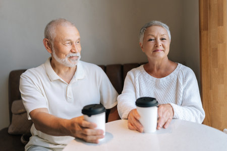 Happy retired couple with gray hair enjoying coffee together in cozy cafe, radiating love and contentment, cherishing every moment of golden years. Concept of active aging and happy retirement.の写真素材