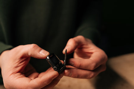 Cropped shot of unrecognizable repairman carefully opening smartwatch to replace battery, demonstrating intricate process of device repair. Concept of process electronic device maintenance.の写真素材