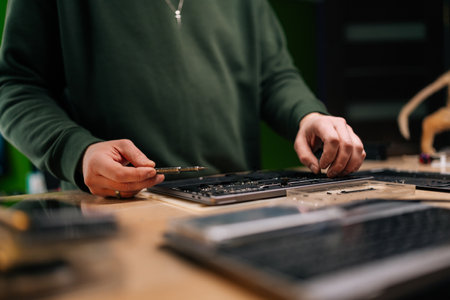 Skilled computer master carefully repairing laptop motherboard, using precision screwdriver while...