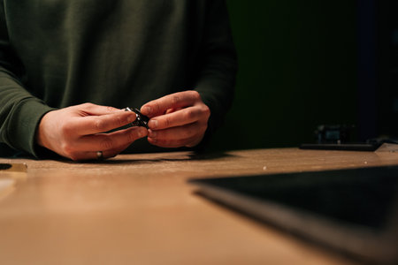 Close-up cropped shot of technician replacing battery of smartwatch using specialized tools, highlighting intricate process of modern device repair. Concept of process electronic device repair.の写真素材