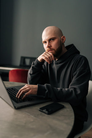 Vertical portrait of puzzled freelancer remote working from home office, sitting at table with laptop computer, analyzing project strategies amid professional challenges and looming deadlines.の写真素材