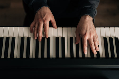 Close-up top view of male hands composer playing synthesizer at home studio. Closeup of talented...