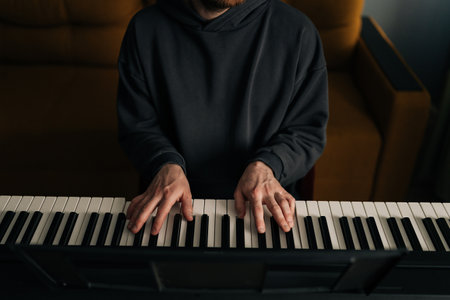 Cropped shot of male composer playing on eclectic piano at home studio. Closeup of talented musician creating beautiful melodic composition using synthesizer. Concept of recording music at homeの写真素材