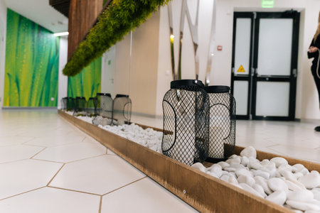 White pebbles and black wire lanterns decorating wooden tray in modern beauty clinic interior with hexagonal floor tiles, green wall, mirror reflecting design elements, no people, nobody.の写真素材