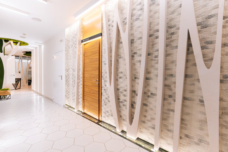 Empty corridor in modern beauty clinic featuring decorative brick tile wall, white curves and led lighting, creating welcoming and relaxing atmosphere, no people, nobody.の写真素材