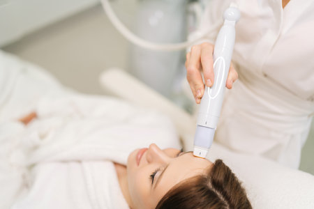 Top view of woman receiving rejuvenation treatment in clinic of aesthetic medicine. Professional aesthetician performing mesotherapy treatment on female, focusing on skin rejuvenation, hydration.の写真素材