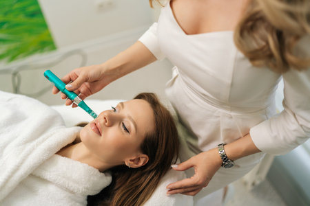 Top view of female patient receiving rejuvenation treatment in cosmetology clinic. Professional beautician performing mesotherapy treatment to young woman focusing on skin rejuvenation, hydration.の写真素材