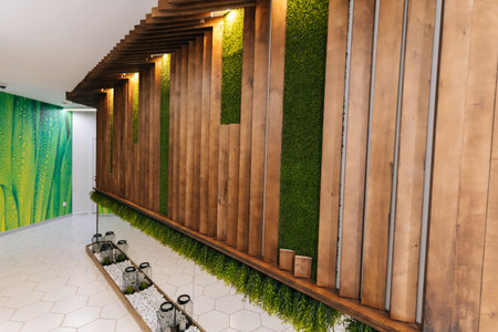 Modern beauty clinic interior with wooden panels and green wall creating relaxing atmosphere in beauty clinic, featuring white hexagonal tiled floor and decorative elements, no people, nobody.の写真素材