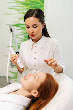 Vertical portrait of focused beautician performing mesotherapy treatment with specialized device on woman facial skin. Concept of non-surgery cosmetology, professional skincare, beauty treatment.の写真素材