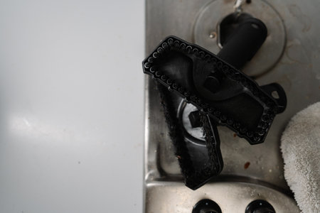 High-angle view of cleaning brush attachment for steam cleaner removing burned food from stove top, showcasing effective cleaning tools for kitchen appliances. Concept of cleanliness, housekeeping.の写真素材