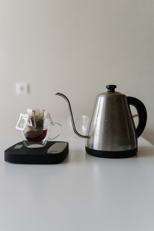Prepared drip coffee with precision using kitchen scale to measure coffee and water for ideal brew. Sleek modern kettle in minimalist kitchen setting on white background, copy space.の写真素材