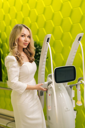 Vertical portrait of aesthetician doctor posing standing by mesotherapy apparatus in modern beauty salon, showcasing innovative technology for skincare treatments in modern aesthetic clinicの写真素材