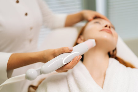 Close-up of female client getting mesotherapy treatment in clinic of aesthetic medicine. Beautician device to mesotherapy treatment on woman chin. Concept of anti-age rejuvenation skincare.の写真素材
