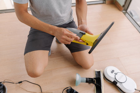 Close-up of unrecognizable service employee kneeling on floor, preparing cordless window cleaning...