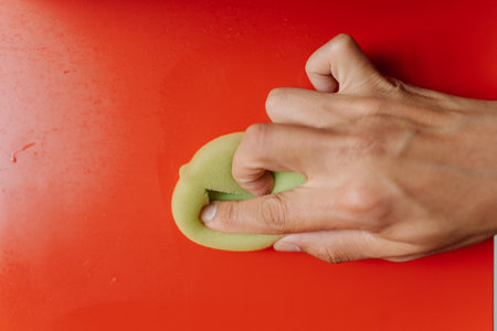 Close-up cropped shot of unrecognizable man using cleaning cloth, wiping dusty dirty red shelf...