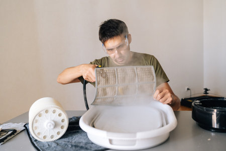 Professional technician wearing protective glasses sanitizing air humidifier using high-temperature...