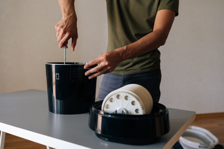 Cropped shot of technician disassembling and performing maintenance on modern black air humidifier...