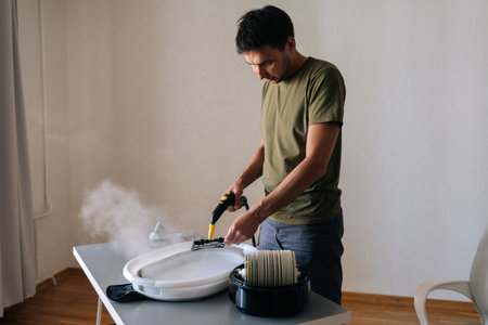 Portrait of focused professional cleaning air humidifier filter with steam cleaner, washing filter in basin for improved indoor air quality and device performance. Concept of cleaning and household.の写真素材