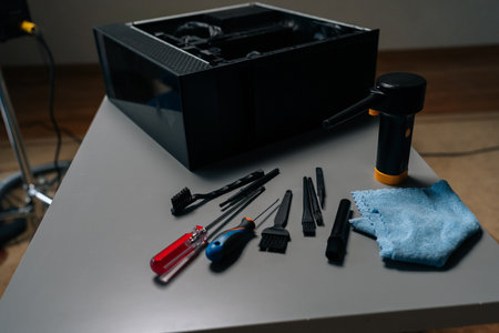 Cleaning open computer case with specialized tools like screwdrivers and brushes on gray table in...
