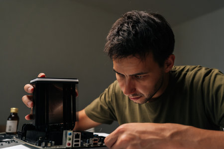 Close-up portrait of skilled computer technician male carefully installing CPU cooler onto...
