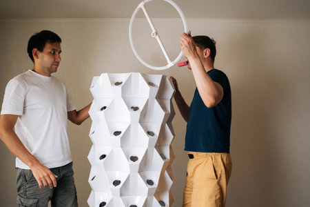 Two agricultural engineers assembling vertical hydroponic tower, showcasing modern approach to...
