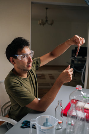 Urban farmer wearing safety glasses examining fertilizer packet while preparing to nourish plants in...