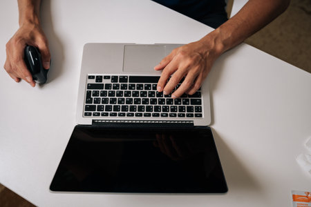 Top view of unrecognizable professional male working at minimalist white desk with ergonomic...