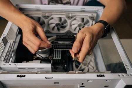 Top view of technician male installing wi-fi module into desktop computer, demonstrating process of upgrading or repairing computer hardware at workshop. Concept of modern technology.の写真素材