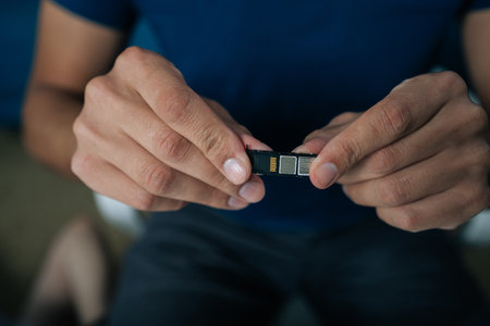 Cropped shot of skilled technician replacing smartphone sim card, demonstrating precise mobile repair technique with professional troubleshooting expertise. Concept of modern communicationの写真素材