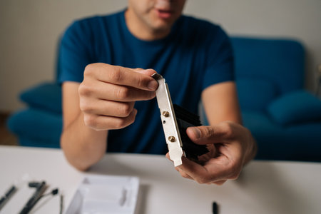Cropped shot of technician male assembling wi-fi module using tools at home office desk, focusing on intricate components and ensuring proper connection. Concept of desktop PC maintenanceの写真素材