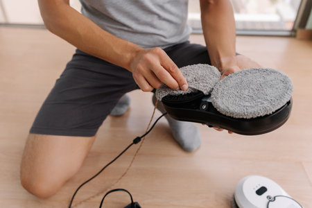 Homeowner preparing robotic window cleaner by changing mop and getting ready to clean windows,...
