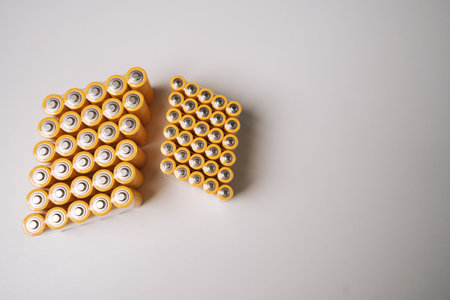 Numerous double batteries arranged in two distinct groups on isolated white background, creating visually striking pattern while highlighting organized collection of energy sources, nobody, no people.の写真素材