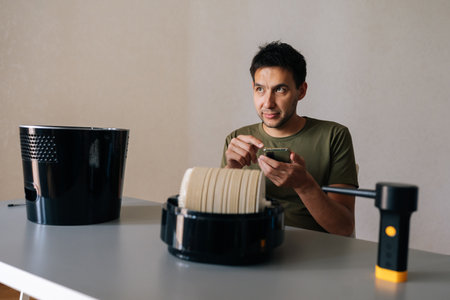 Man sitting at table and cleaning air humidifier filter, using instructions or tutorial on...