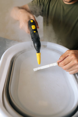 Vertical cropped shot of unrecognizable man using steam cleaner for sanitizing humidifier filter...