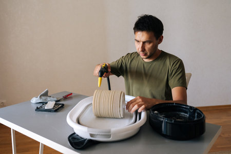 Portrait of young man cleaning humidifier filter with steam cleaner, ensuring clean and healthy air...