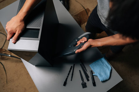 Top view of computer technician cleaning computer case with vacuum cleaner, different brushes and...
