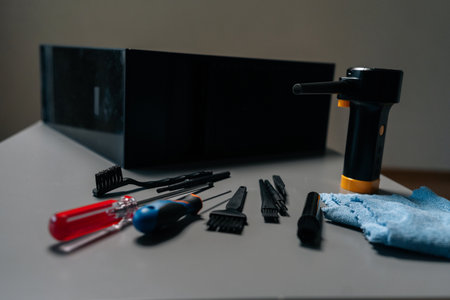 Close-up of cleaning open computer case with specialized tools, screwdrivers and brushes on gray...