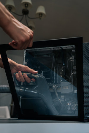 Close-up vertical shot of technician using vacuum cleaner to remove dust and debris from inside...