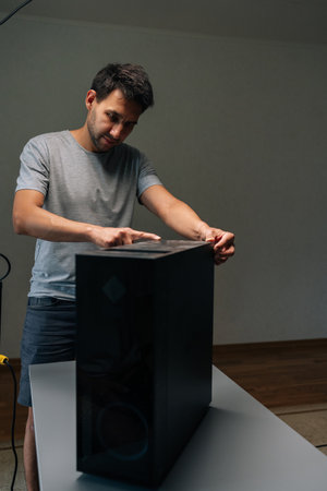 Vertical portrait of computer technician pointing at layer of dust on computer case, highlighting...
