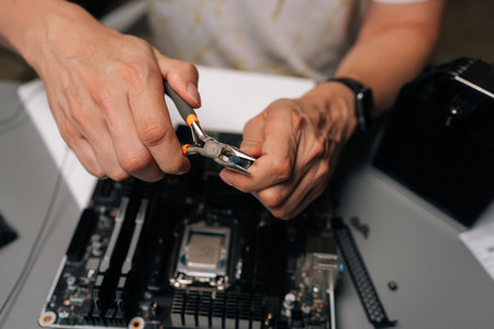Computer technician unpacking new thermal paste using pliers, preparing for maintenance or upgrade...
