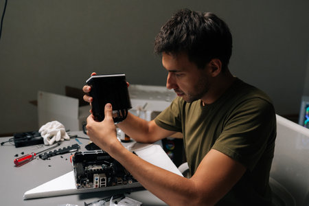 Side view of computer technician installing CPU cooler onto motherboard, performing maintenance or...