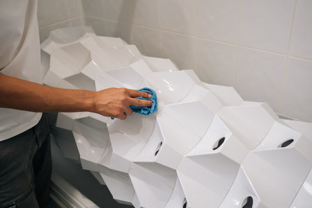 Person wiping white hydroponic system with blue cloth, maintaining pristine growing environment for...