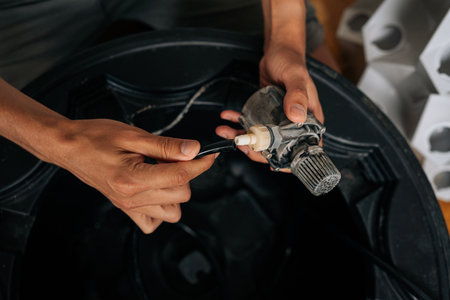 Close-up cropped shot of unrecognizable home gardener installing water pump on vertical hydroponic tower, configuring soilless indoor growing system for fresh plant cultivation.の写真素材