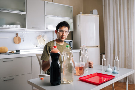 Agricultural technician wearing safety glasses preparing fertilizer in home kitchen laboratory, mixing various liquids and using syringe for diy gardening approach. Concept of urban farming.の写真素材
