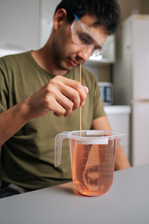 Agricultural technician wearing protective eyewear mixing chemical solution with stirrer inside...