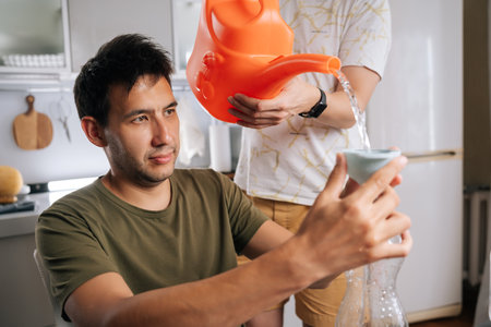 Two home gardening enthusiast preparing fertilizer for plants in home kitchen, mixing water and...