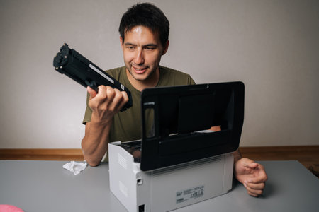 Cheerful computer technician replacing toner cartridge in laser printer during maintenance service,...