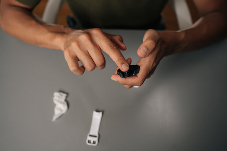 Close-up of hands cleaning smartwatch with disinfectant wipe, emphasizing hygiene and device care in contemporary setting with spare white watch band nearby. Concept of healthy lifestyle.の写真素材