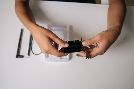 Close-up cropped shot of technician male installing wi-fi module with heatsink into computer, upgrading wireless network card for improved connectivity. Concept of desktop PC maintenance and service.の写真素材