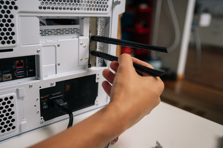 Technician male installing wifi module with two antennas into desktop computer case, enhancing connectivity and network performance, during upgrading or assembling PC at workshopの写真素材